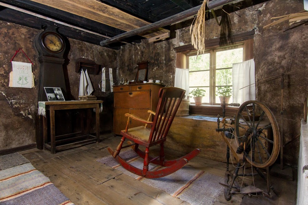 Trömperi Kestikievari inn from inside: Old big cabin and cabin furniture, rug, rocking chair, cabinet clock, cabinets, dishes