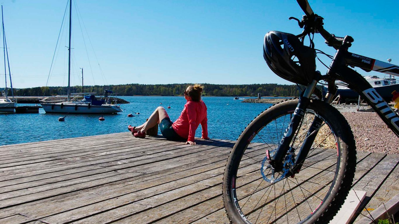 Woman sitting on pier with a bicycle in front